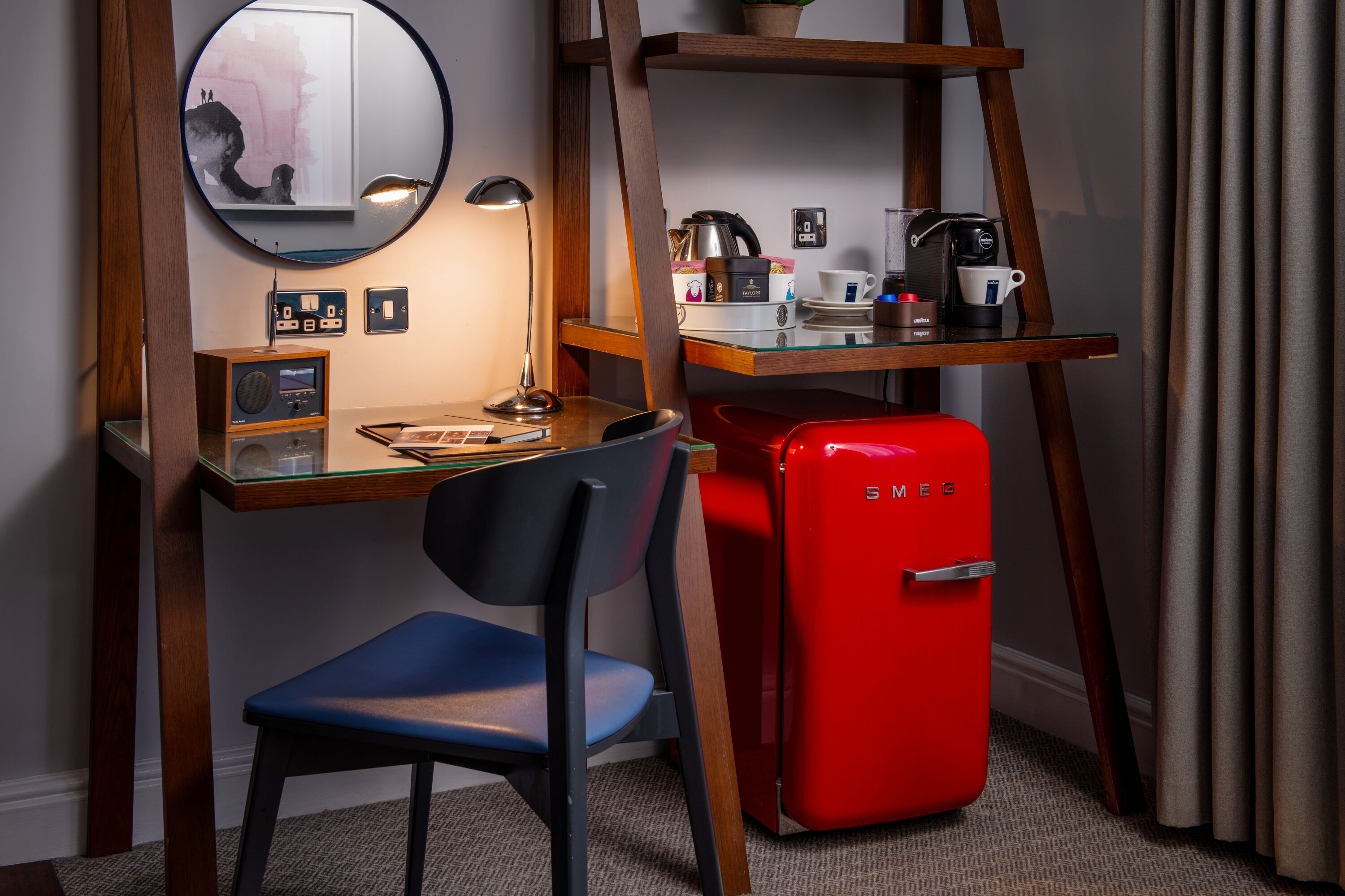 Un espacio de trabajo funcional con escritorio, silla y un refrigerador rojo Smeg.