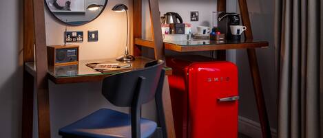 Un espacio de trabajo funcional con escritorio, silla y un refrigerador rojo Smeg.
