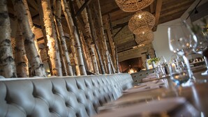 Un restaurant doté d’un long banc capitonné, de poutres en bois et de luminaires suspendus en fibres tressées.