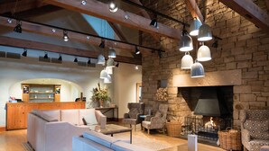 Un vaste espace de vie agrémenté d’une cheminée en pierre, de canapés en cuir et de luminaires suspendus.