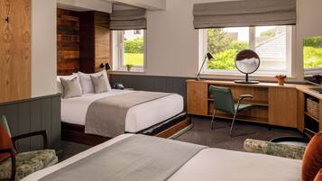 Habitación de hotel con dos camas, un escritorio, una silla, un espejo y vistas al jardín.