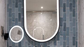 Un baño con lavabo, espejo y pared de azulejos.