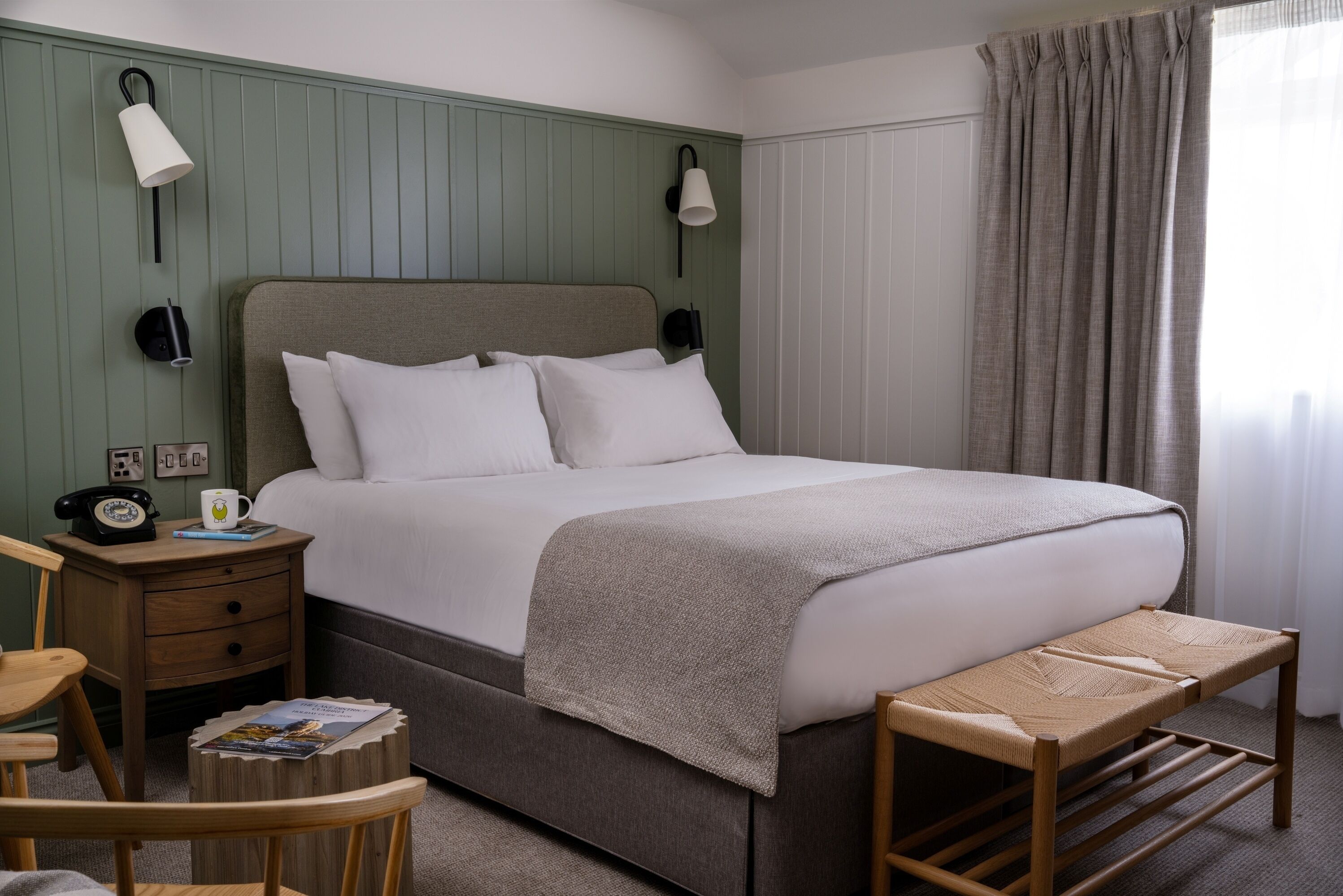 A neatly arranged bedroom with a bed, bedside tables, a chair, and a small table.