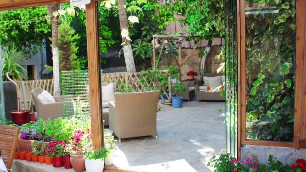 A patio area with wicker furniture, potted plants, and a wooden pergola. - Divas Hotel (Istanbul)
