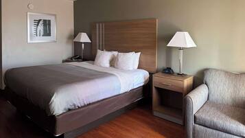 Habitación de hotel con cama, mesitas de noche, una silla y un reloj en la pared.