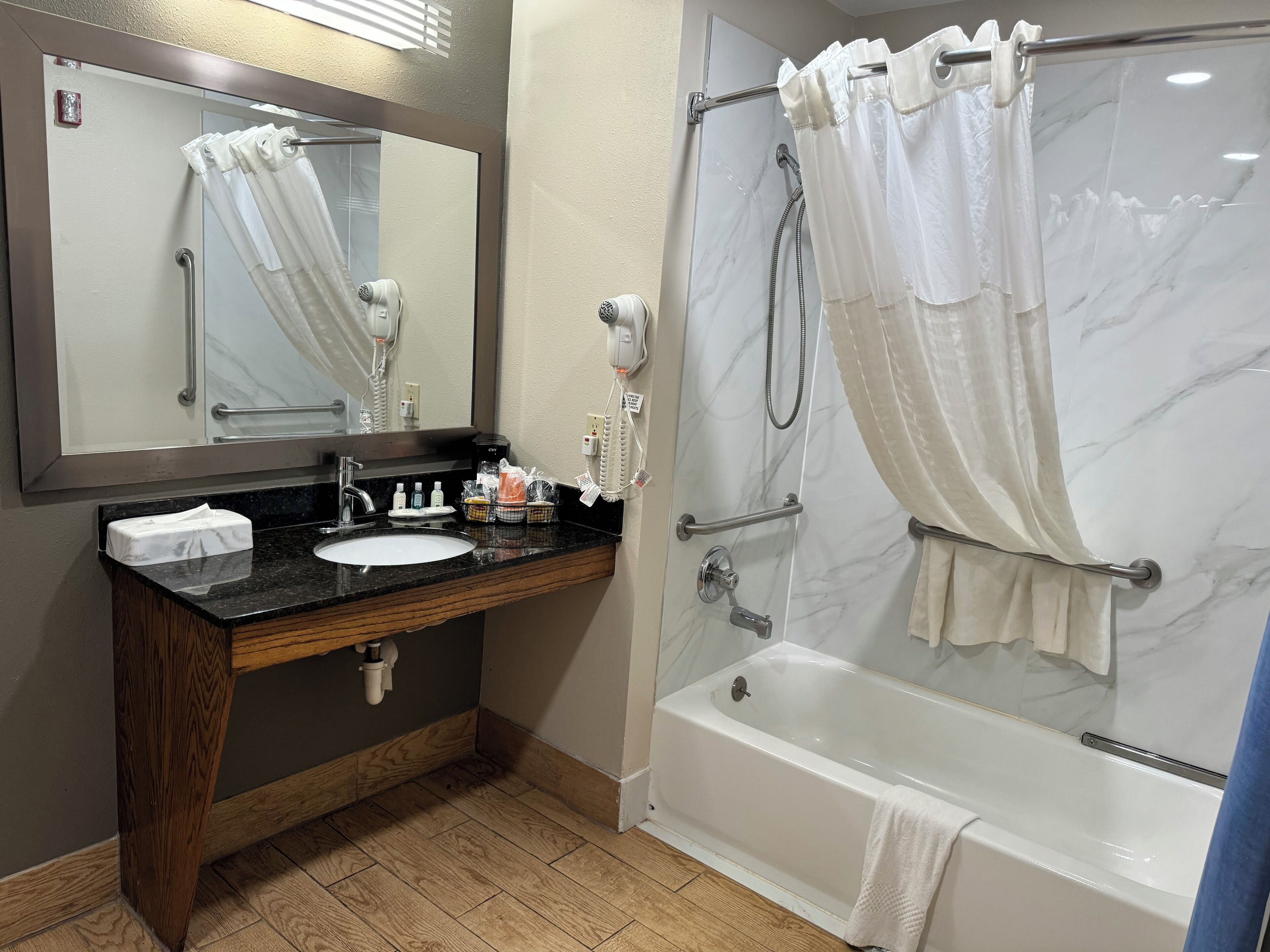 Une salle de bain avec une douche en marbre, un lavabo avec des articles de toilette et un miroir.