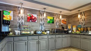 Una cocina moderna con armarios grises, una exposición de frutas y un dispensador de zumo.