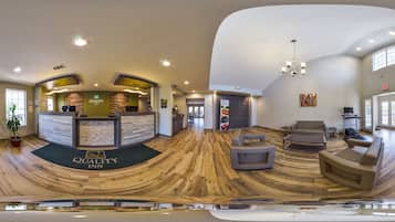 A modern hotel lobby with a reception desk, seating area, and a large window.
