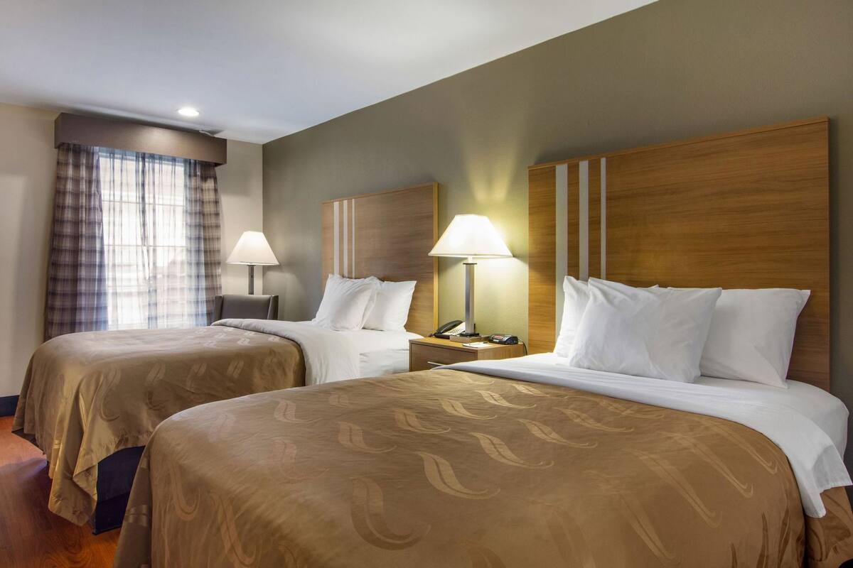 Habitación de hotel con dos camas, un escritorio, una lámpara y un teléfono.