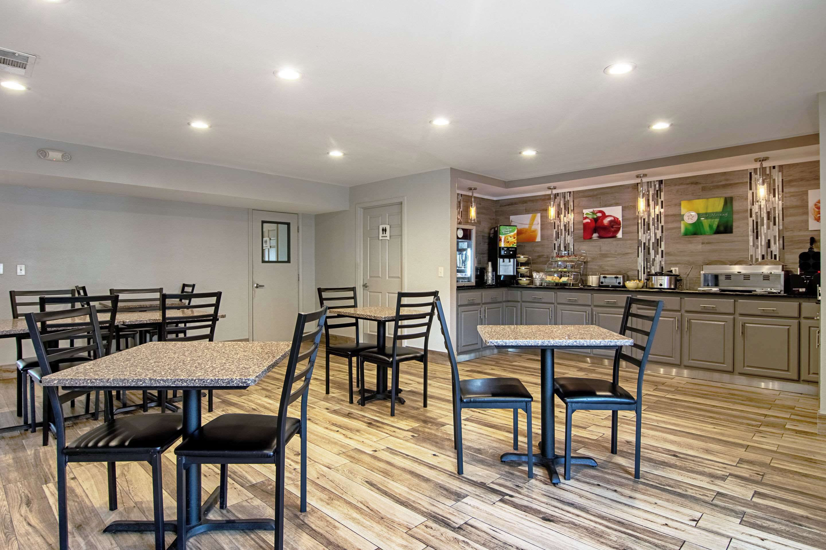 A modern kitchen with granite countertops, stainless steel appliances, and a wooden floor.