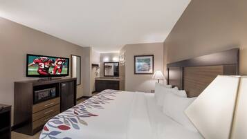 Een hotelkamer met een bed, een televisie, een bureau met een computer, en een badkamer op de achtergrond.
