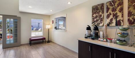 A modern kitchen with a bench, a coffee maker, and a view of the outside.