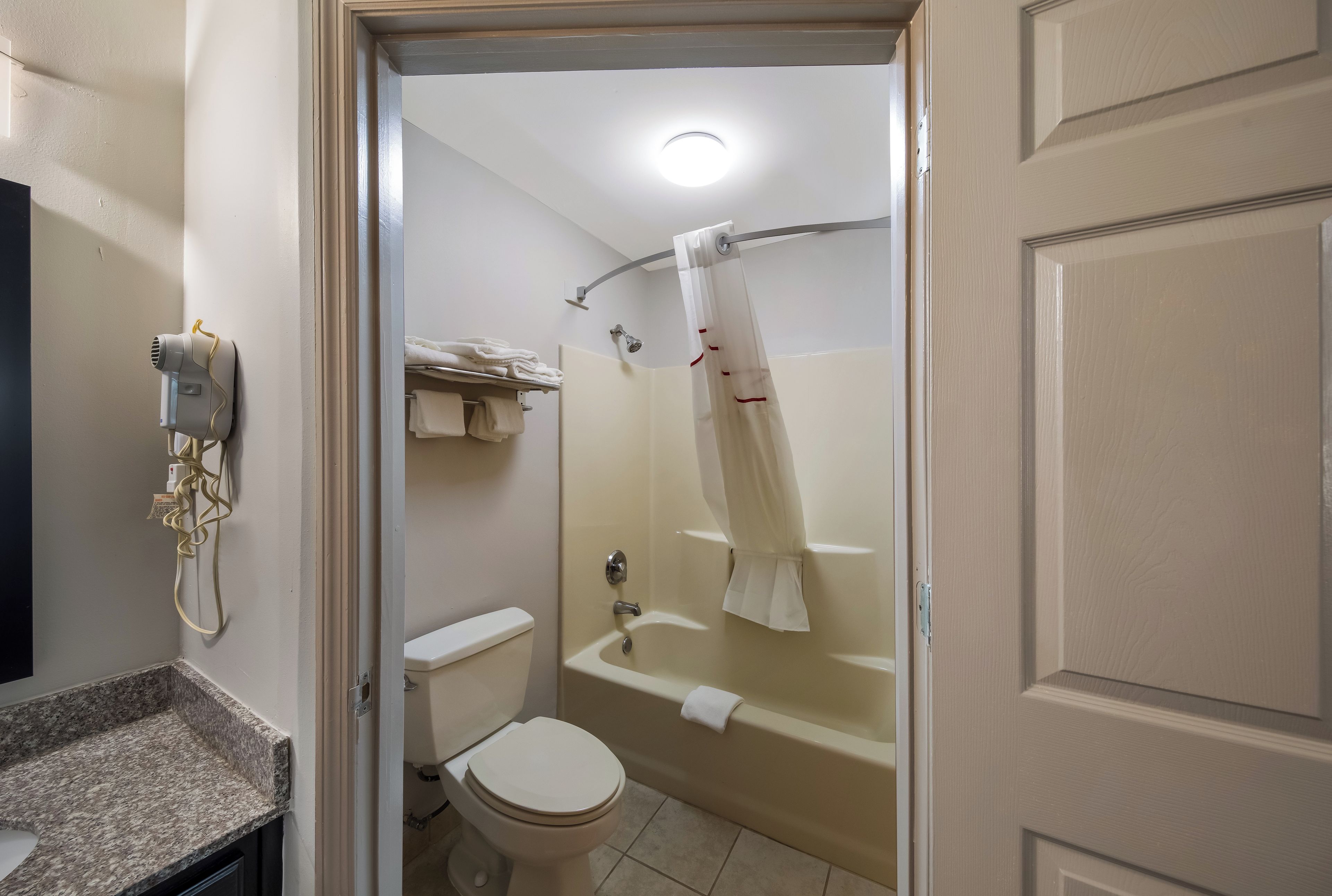 A bathroom with a toilet, a sink, a shower, and a hairdryer.