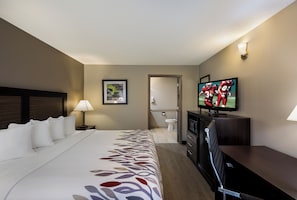 A hotel room with a bed, a television, a desk, and a bathroom visible through an open door. - Red Roof Inn Jasper (Jasper)