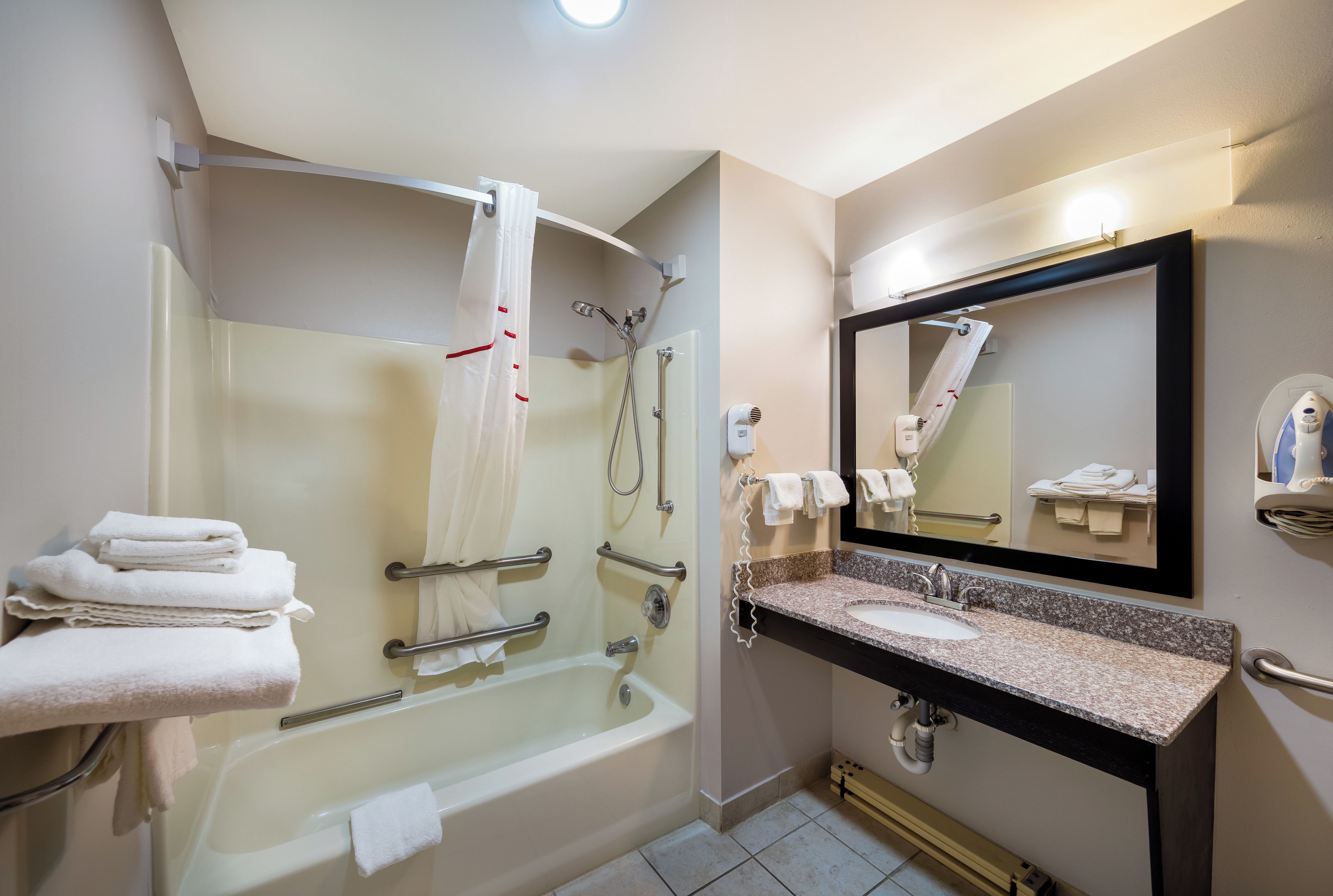 A modern bathroom with a glass-enclosed shower, a vanity with a granite countertop, and a large mirror.