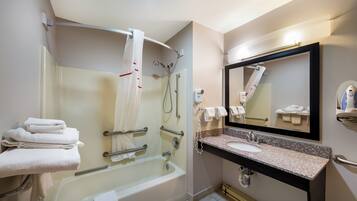 A modern bathroom with a glass-enclosed shower, a vanity with a granite countertop, and a large mirror.