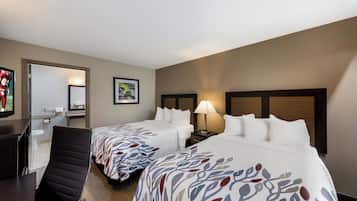 Une chambre d’hôtel avec deux lits, un bureau, une chaise, une salle de bain et un téléviseur.