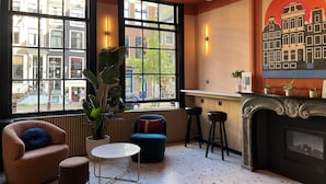 A cozy interior with large windows, a fireplace, and comfortable seating. - Heart Of Amsterdam - Hostel (Amsterdam)