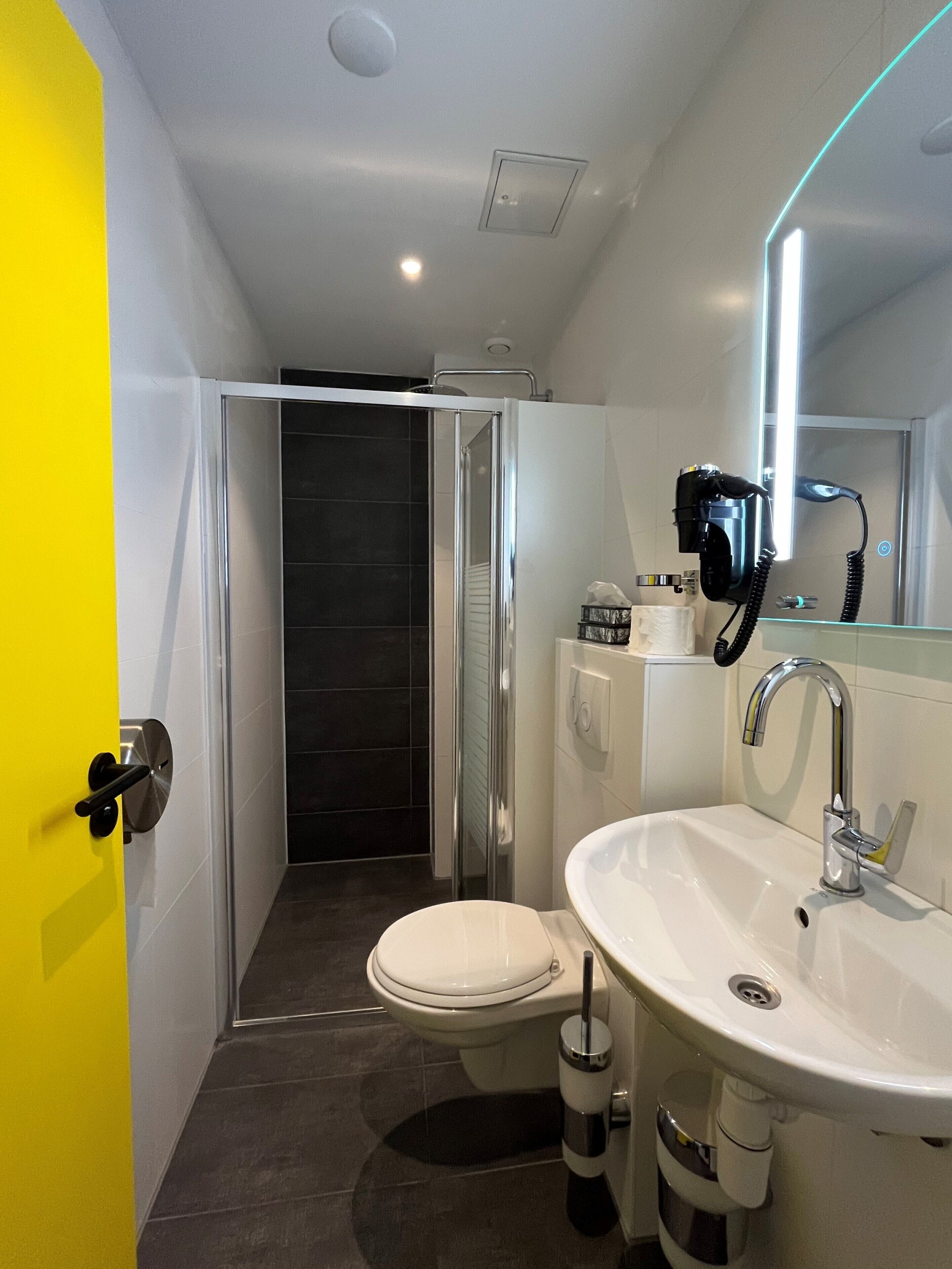 A modern bathroom with a toilet, sink, and shower.