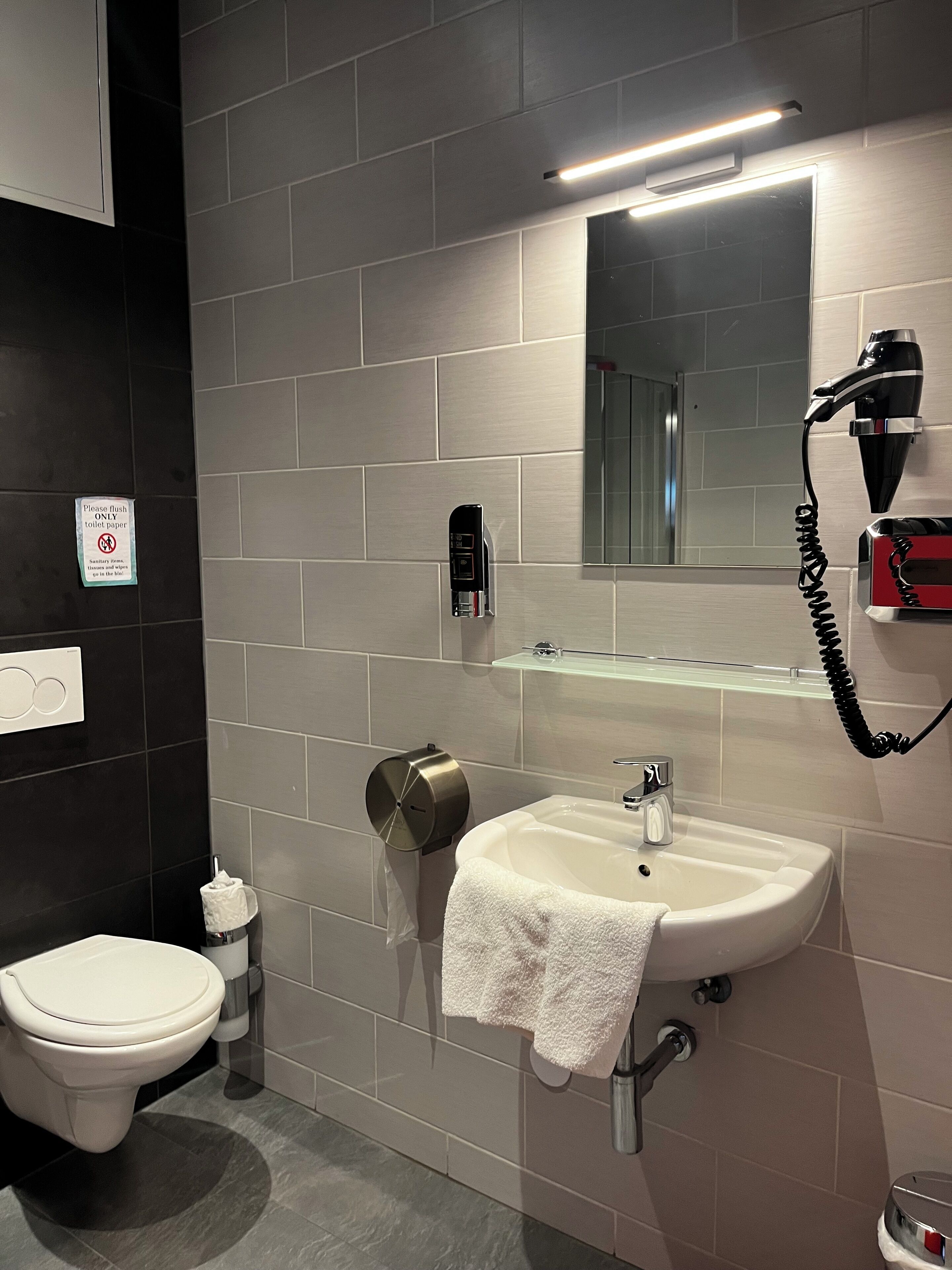 Ein modernes Badezimmer mit Toilette, Waschbecken und Haartrockner.