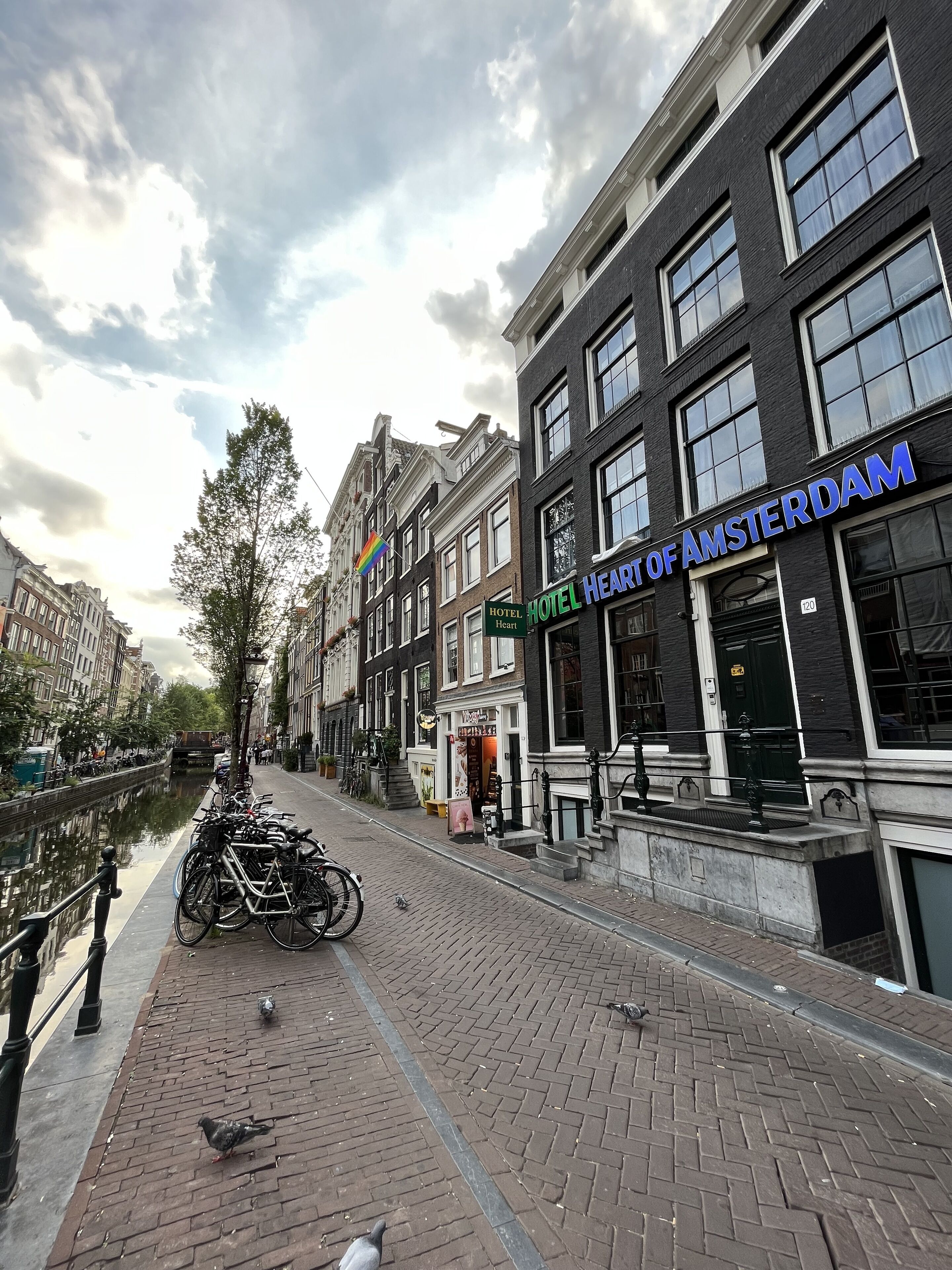 Eine Straße am Kanal mit Gebäuden, darunter das Hotel "Hotel Heart of Amsterdam".