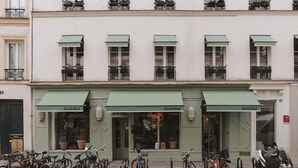 Una fila de toldos verdes con el nombre 'Suivi Blue' sobre una fachada. Hay bicicletas estacionadas adelante, y una moto está aparcada en la acera.