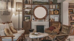 Un salón acogedor con chimenea, asientos cómodos y una estantería llena de libros y objetos decorativos.