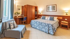Une chambre d’hôtel comprenant un lit, un bureau, une chaise, une armoire et une table de chevet.