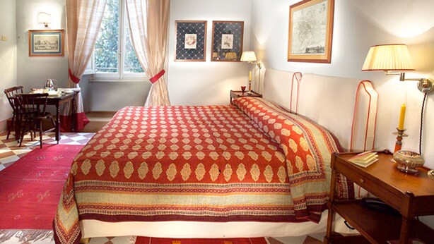 Une chambre à coucher avec un grand lit, un bureau, une chaise et une fenêtre avec des rideaux.