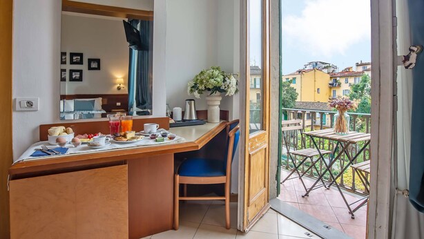 Une chambre d’hôtel avec balcon, un coin repas où le petit-déjeuner est servi, et une vue sur la ville.