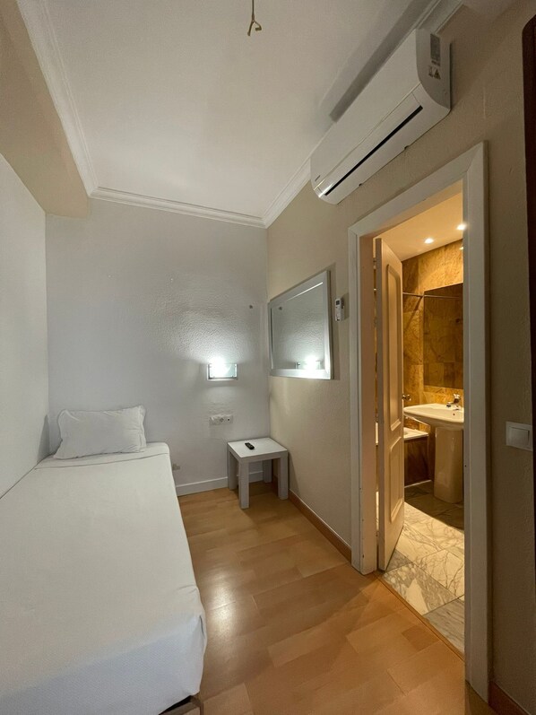 Ein Hotelzimmer mit einem Bett, einem kleinen Tisch, einem Spiegel und einer Klimaanlage.