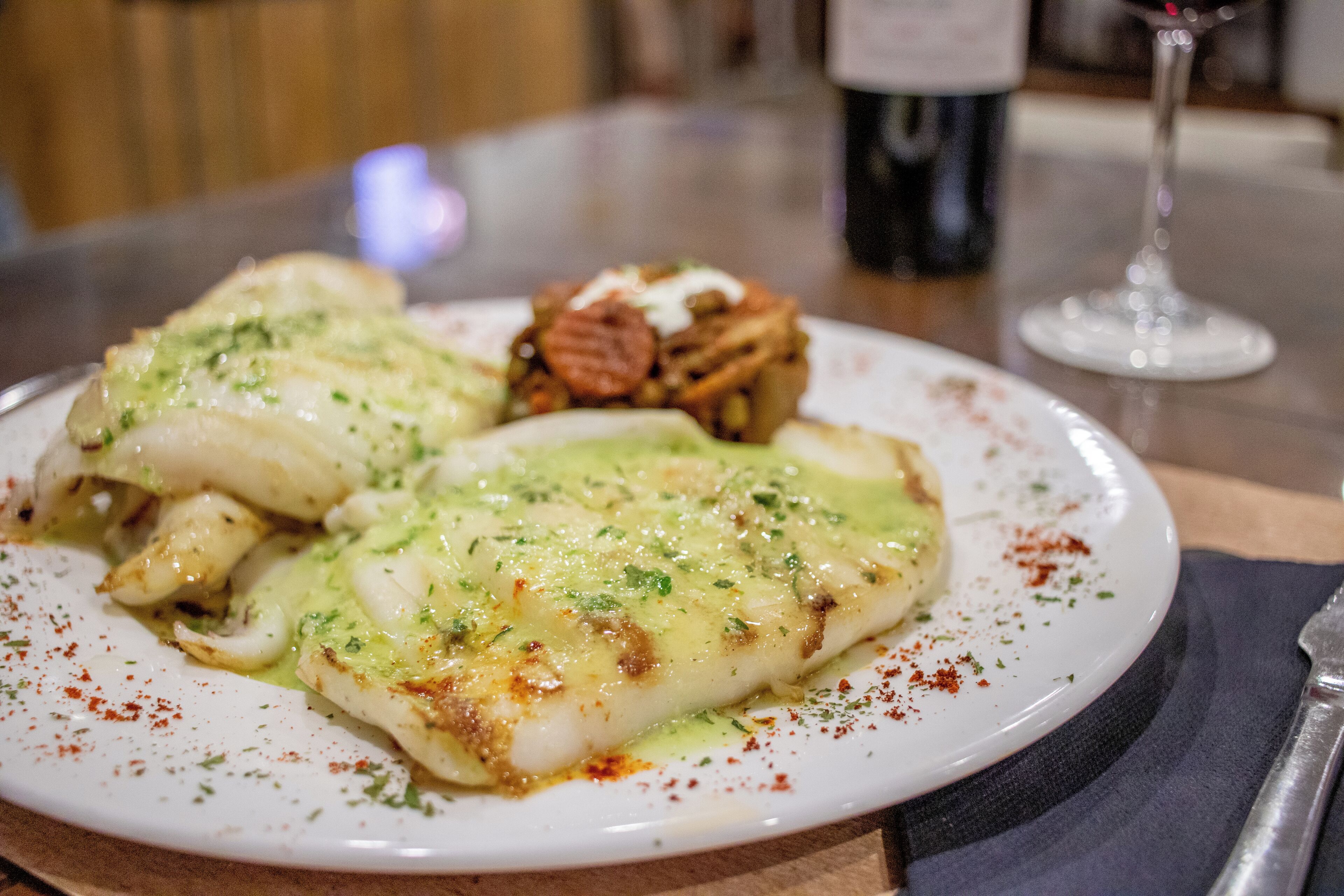 A plate of food with a white plate, a fork, and a wine glass.