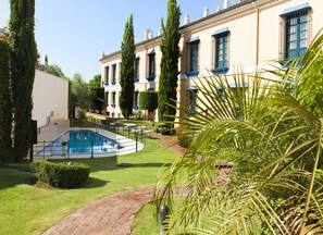 Un área de piscina con diseño circular, rodeada por un césped cuidado y un sendero de ladrillo.