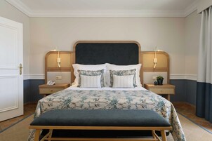 A neatly arranged hotel room with a large bed, two bedside tables, a bedside lamp, and a small potted plant.
