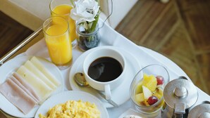 Bandeja de desayuno con huevos revueltos, tostadas, jamón, fruta y jugo.