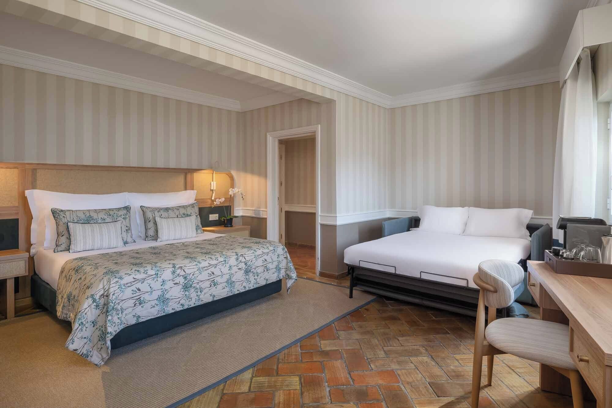 A hotel room with two beds, a desk, and a chair.