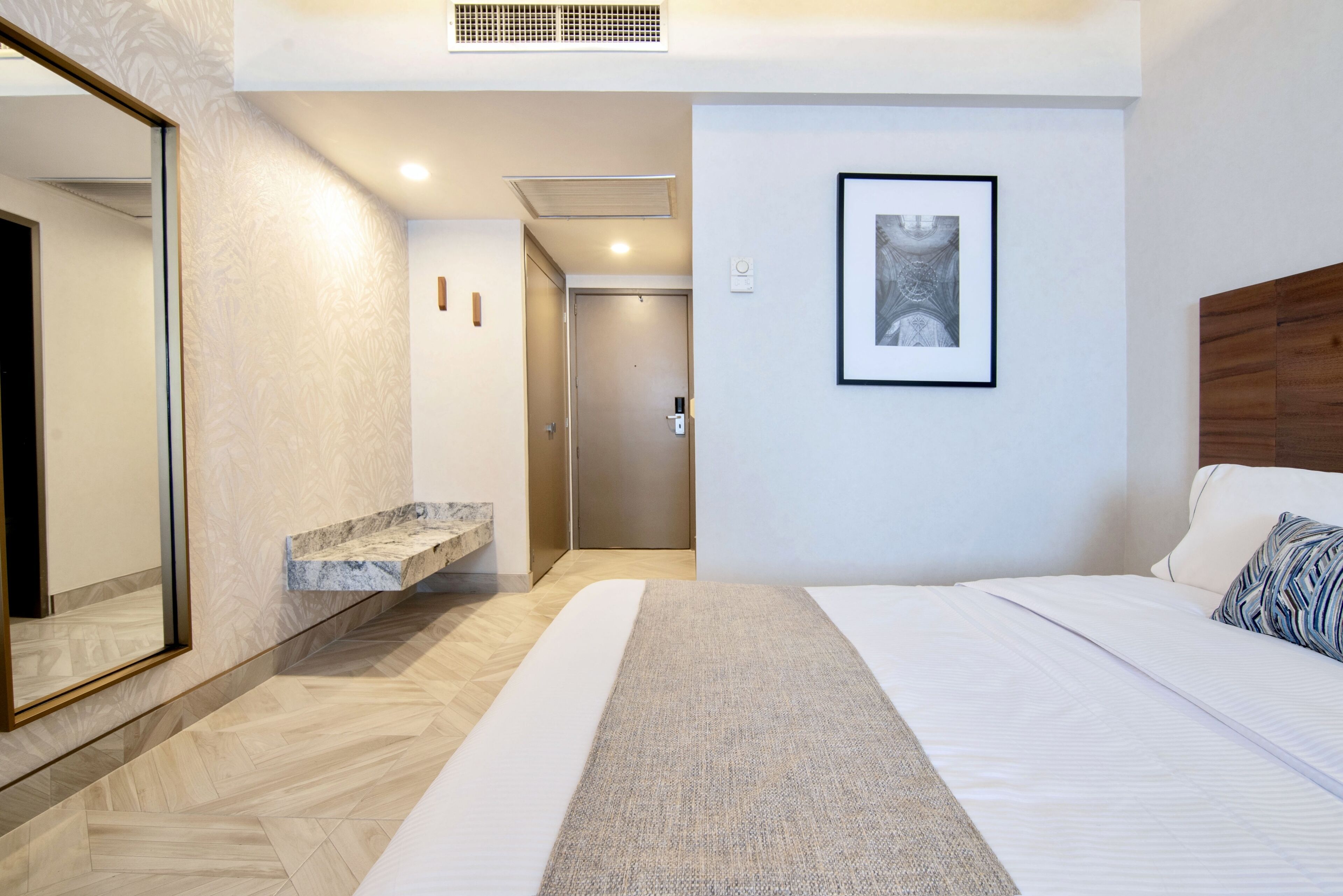 Una habitación de hotel moderna con una cama grande, un baño con encimera de mármol y una obra de arte enmarcada en la pared.