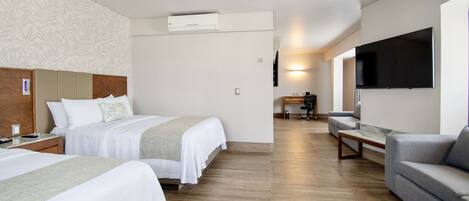 Una habitación de hotel con dos camas, un sofá, un televisor y un equipo de aire acondicionado.