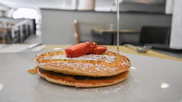 Una pila de tortitas con jarabe y una fresa en un plato.