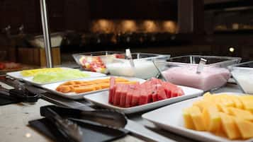 Un bufé con diversos alimentos, entre ellos frutas y postres.