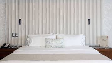A hotel room with a large bed, two bedside tables, a nightstand, a telephone, and a decorative item on the nightstand.