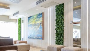 A modern lobby with a large painting, green wall, and seating area.