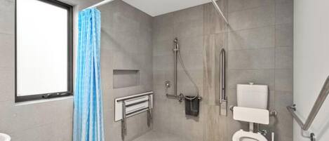 Un baño moderno con ducha, inodoro y ventana.