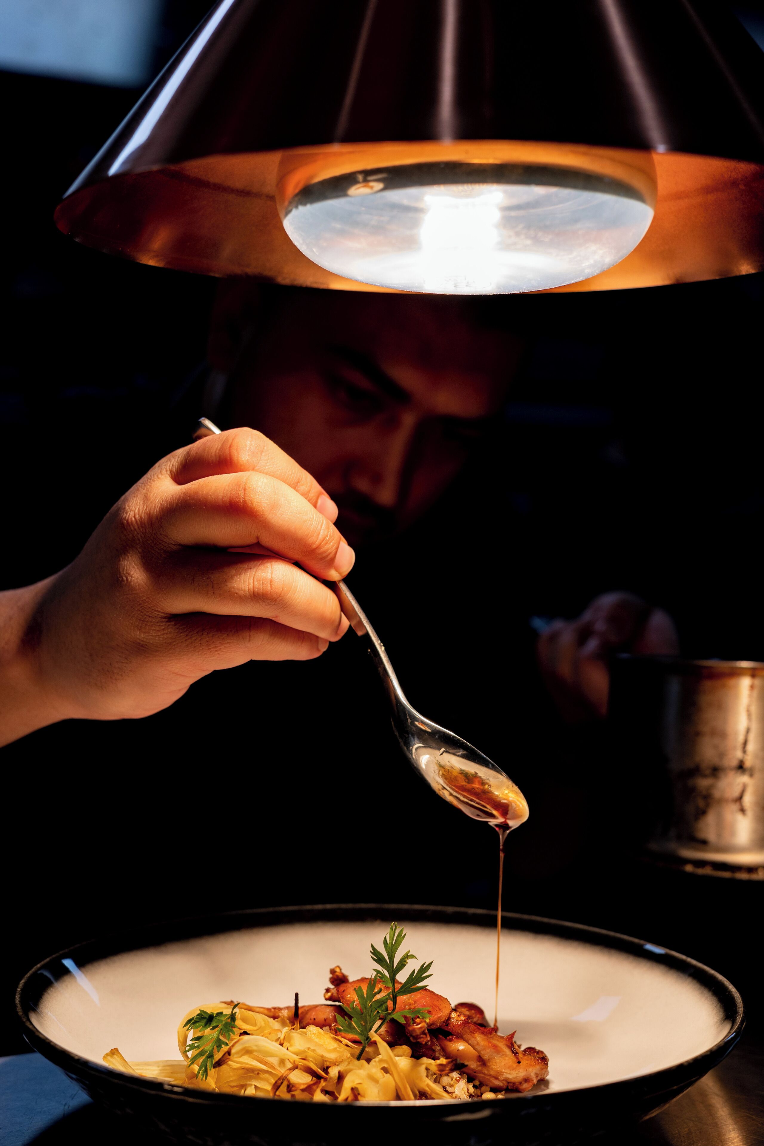 A person dining at a table with a bowl of food and a spoon.