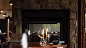 Un interior de restaurante con chimenea de piedra, mesas y sillas de madera.