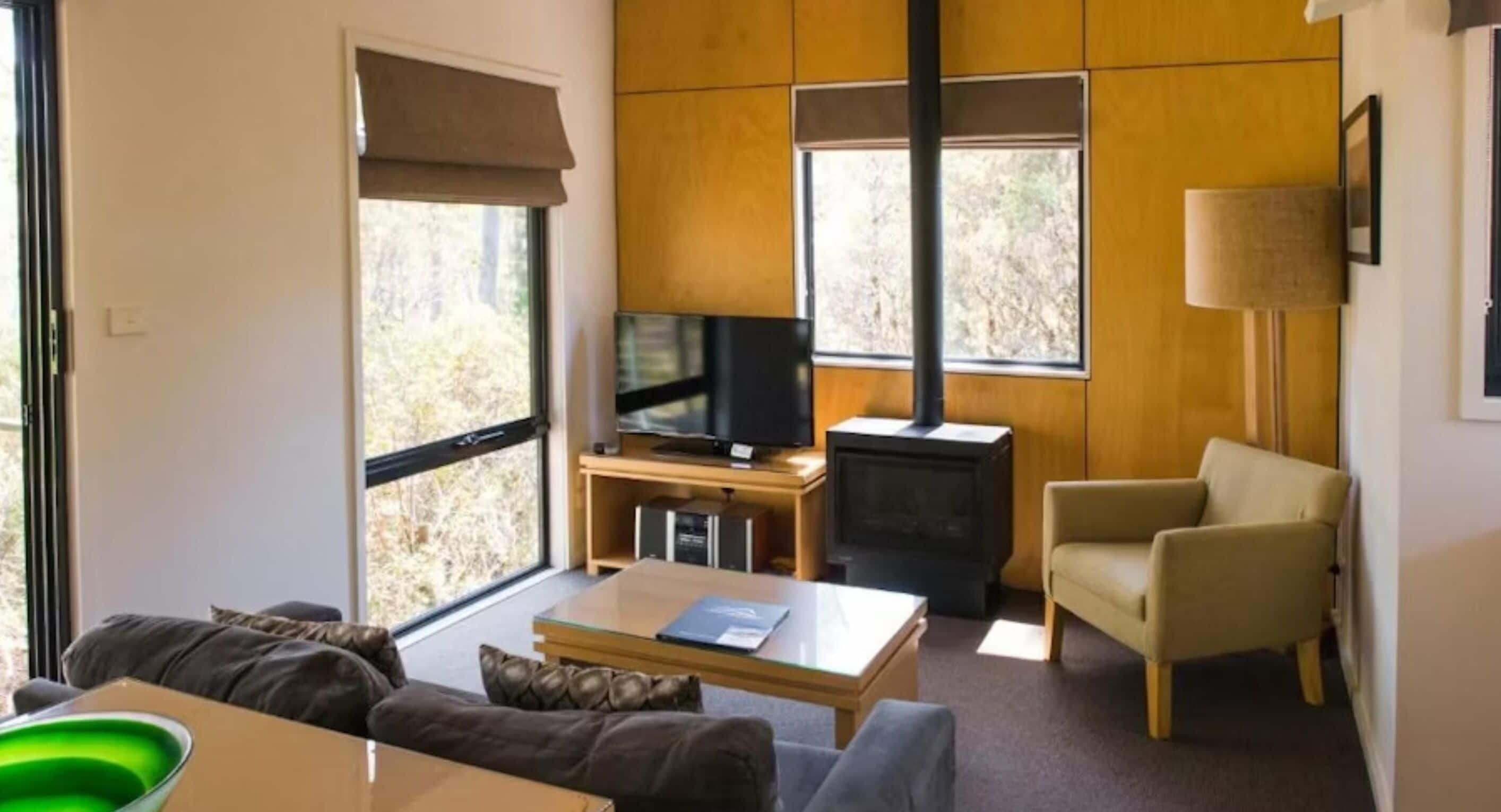 A living room with a sofa, coffee table, TV, fireplace, and a chair.