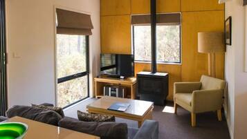 A living room with a sofa, coffee table, TV, fireplace, and a chair.
