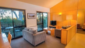 Una sala moderna con un sofá, un televisor y un comedor con sillas y una mesa.