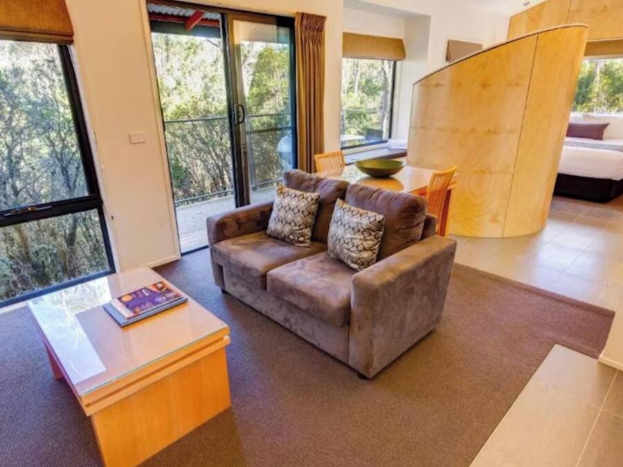 A modern room with a sofa, a small table, and a bed.