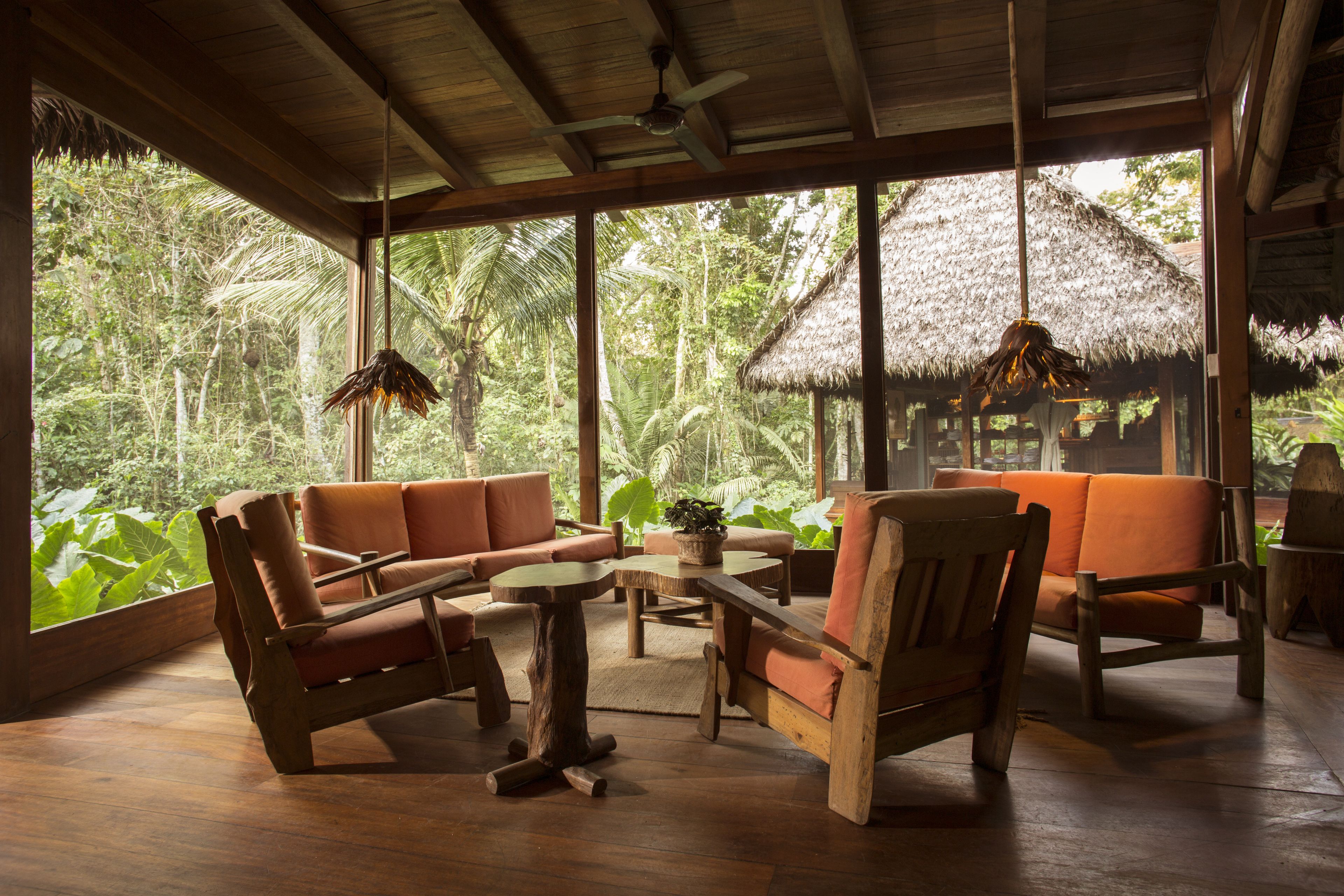 A room with wooden furniture, large windows, and a view of lush greenery.